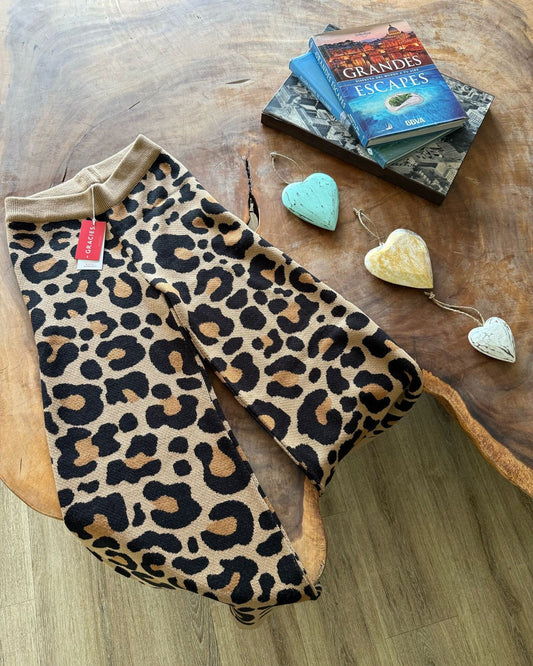 Leopard print pants on a wooden surface with books and heart-shaped objects.